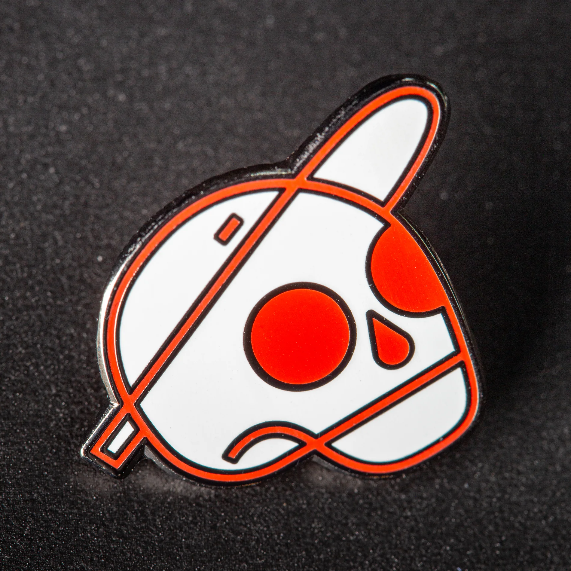 Reece Parker enamel illustration pin against dark textured fabric